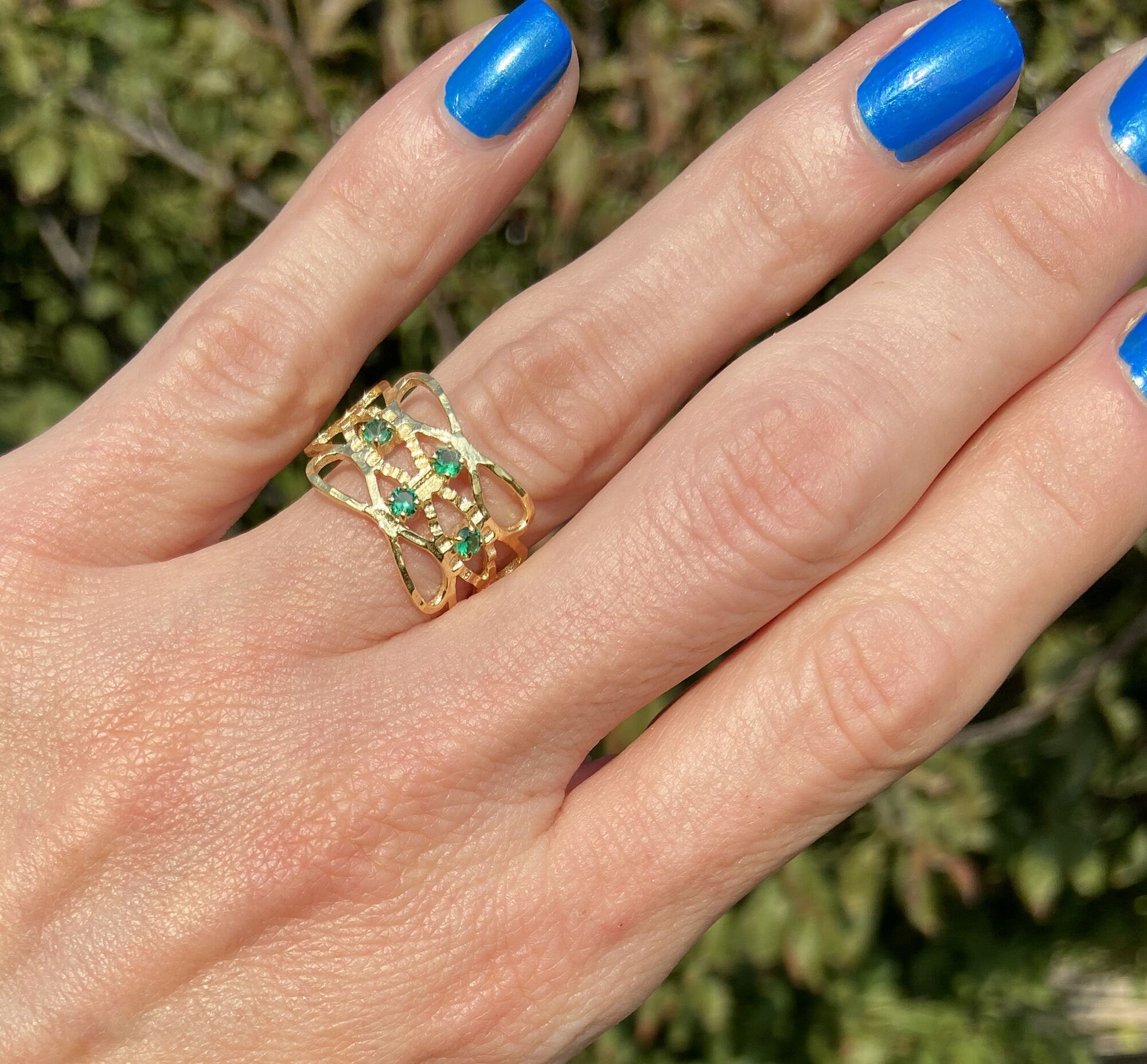 This gorgeous emerald ring displays simple elegance in its design. The ring features a round-cut emerald gemstones and finished with a hammered band.