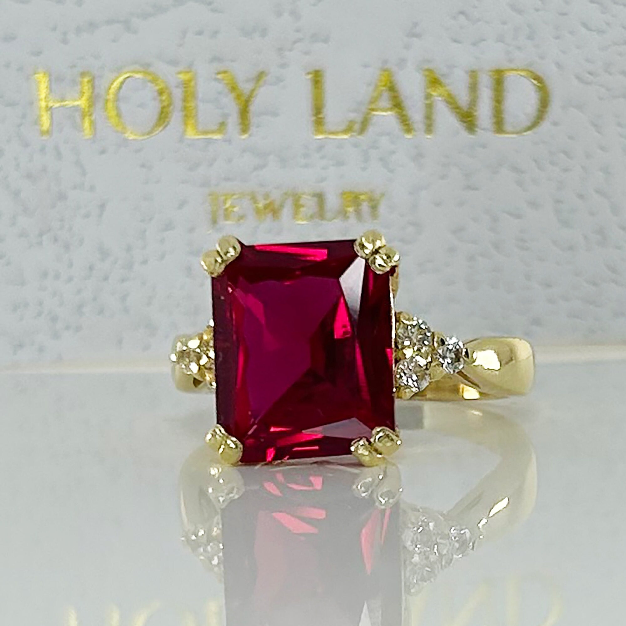 An absolute stunner, classic ruby engagement ring with an emerald cut gemstone of your choice as it’s centre stone and with round cut clear quartz on the band to further accentuate it.