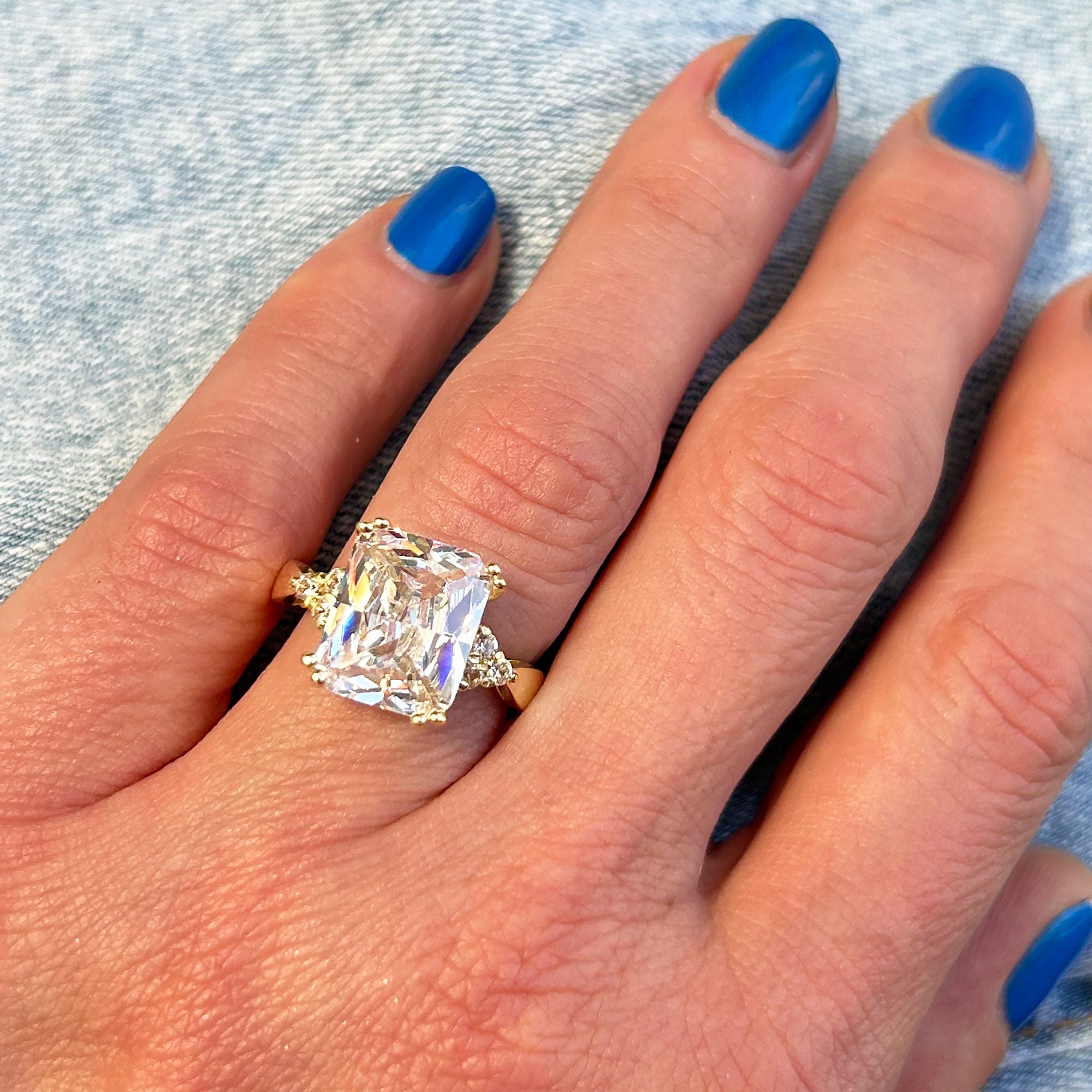 An absolute stunner, classic clear quartz engagement ring with an emerald cut gemstone of your choice as it’s centre stone and with round cut clear quartz on the band to further accentuate it.