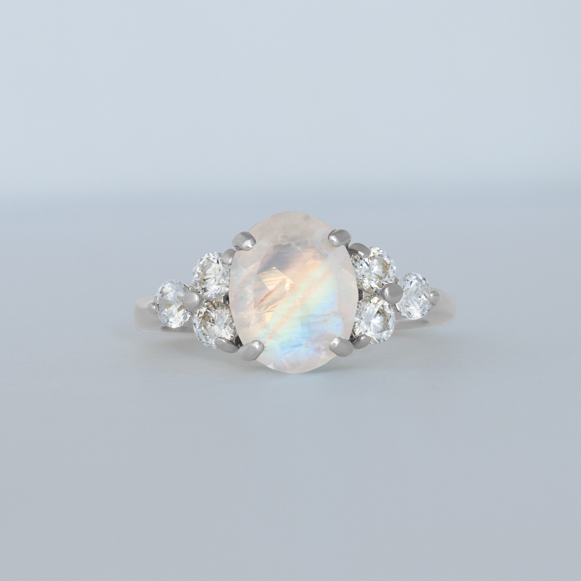 An absolute stunner, classic natural moonstone engagement ring with an oval cut gemstone of your choice as it’s centre stone and with round cut clear quartz on the band to further accentuate it.