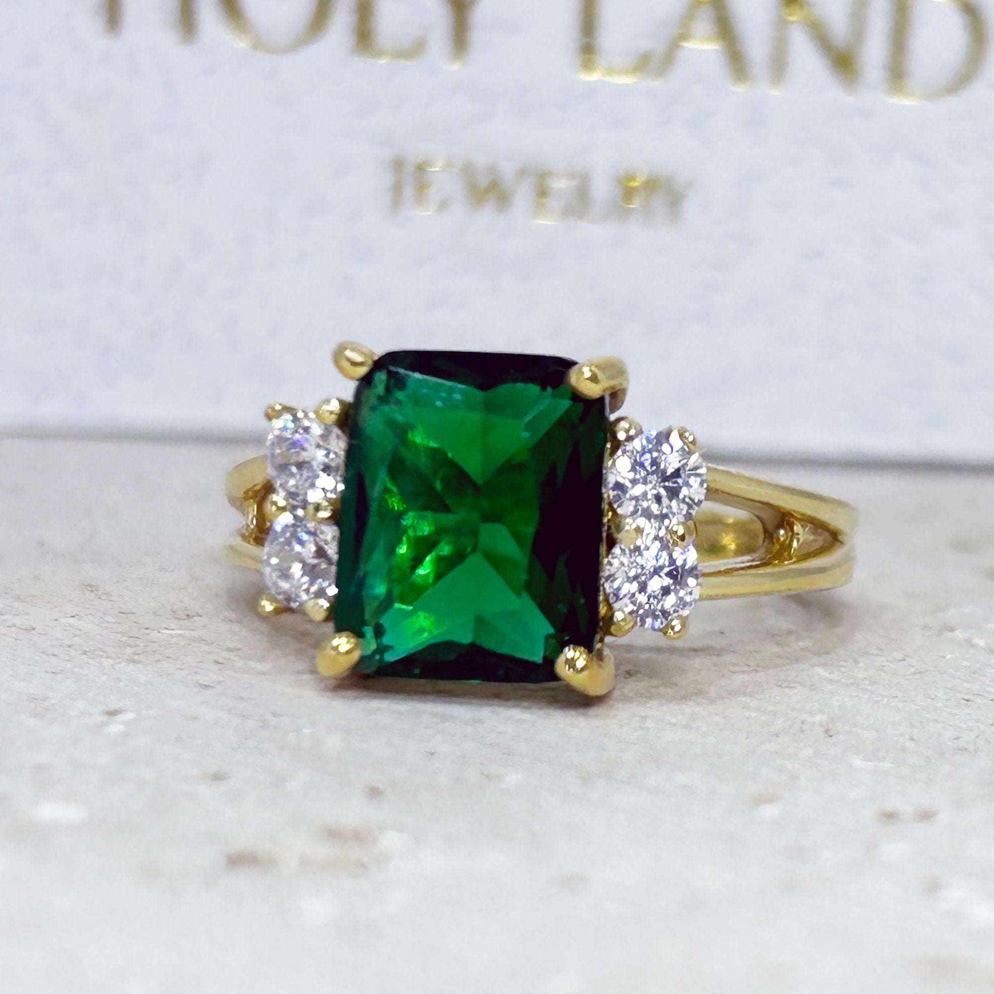 An absolute stunner, classic emerald engagement ring with an emerald cut gemstone of your choice as it’s centre stone and with round cut clear quartz on the band to further accentuate it.