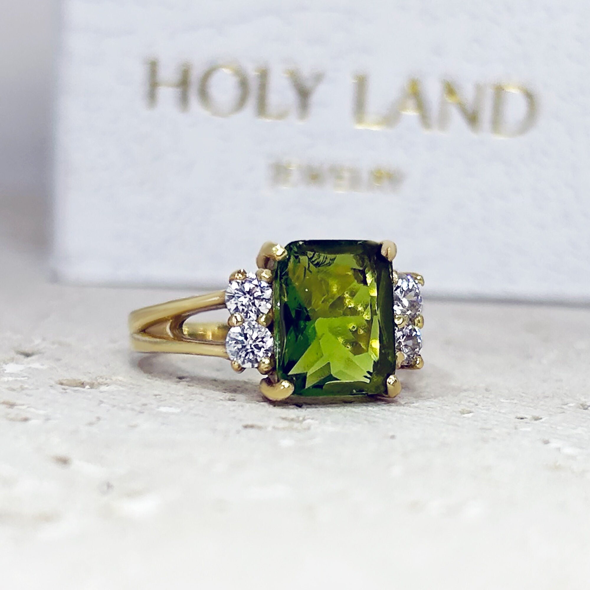 An absolute stunner, classic peridot engagement ring with an emerald cut gemstone of your choice as it’s centre stone and with round cut clear quartz on the band to further accentuate it.