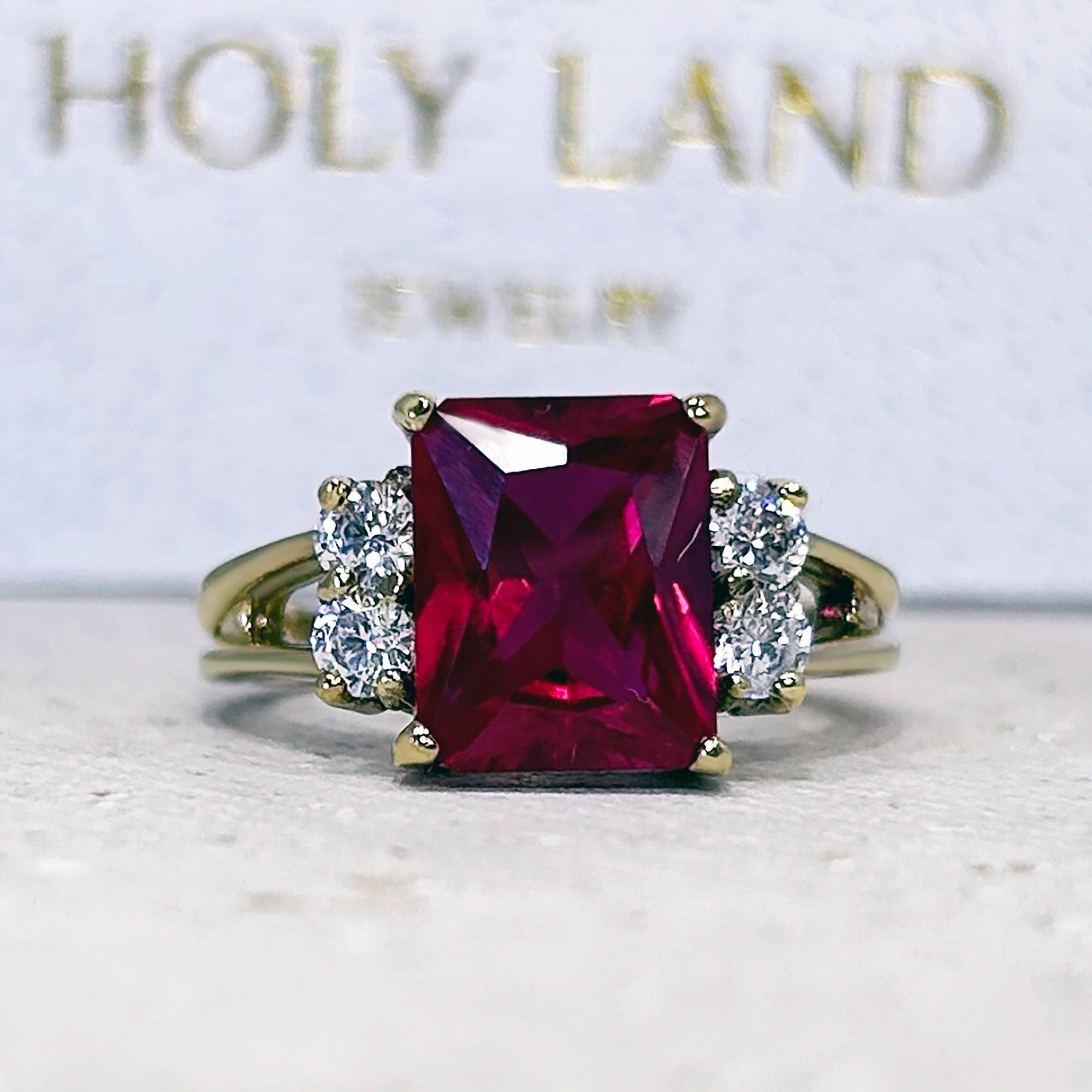 An absolute stunner, classic ruby engagement ring with an emerald cut gemstone of your choice as it’s centre stone and with round cut clear quartz on the band to further accentuate it.