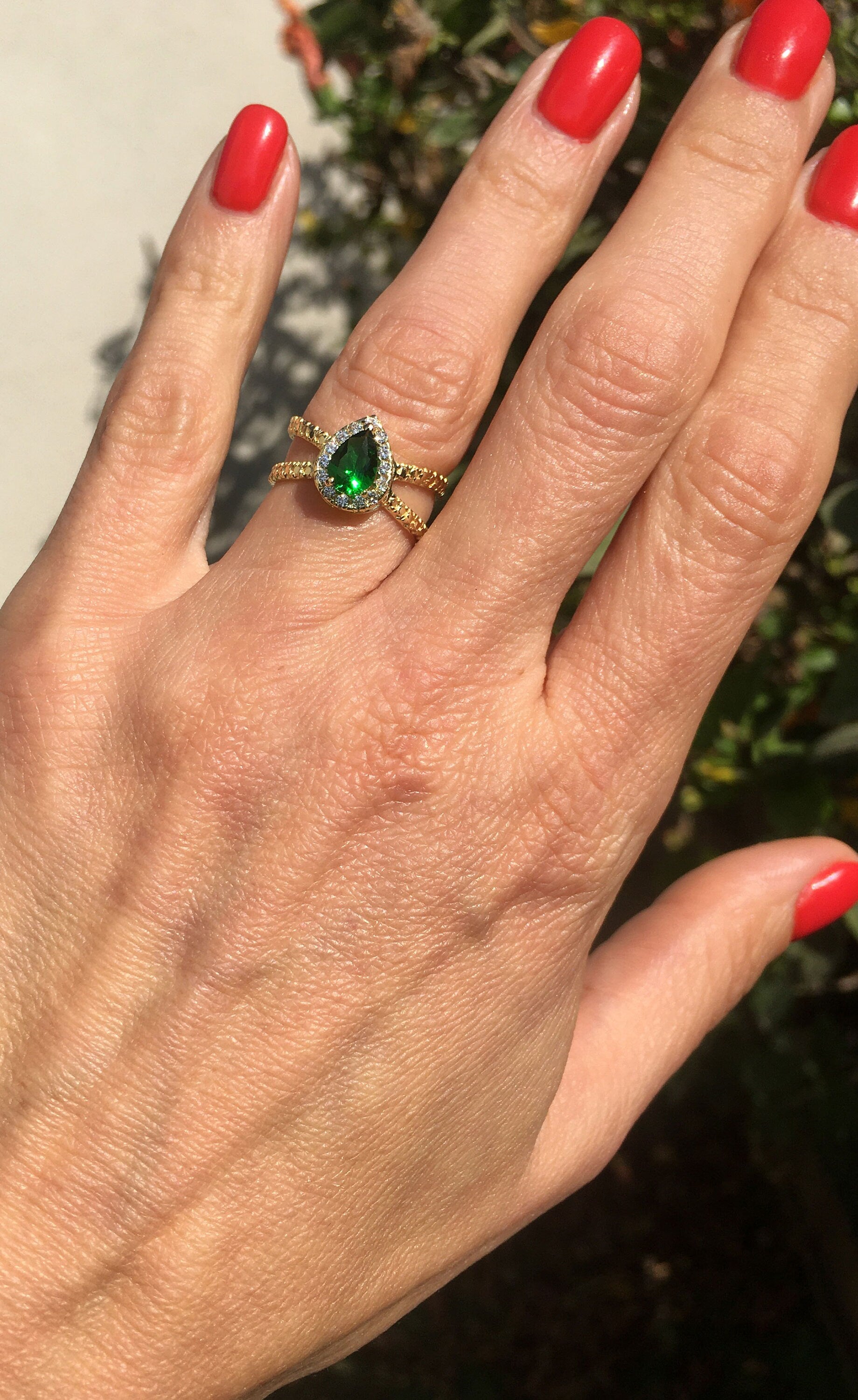 The spectacular design of this emerald ring is a contemporary take on a classic choice which will be much loved by anyone who loves bright and bold jewelry. The pear cut emerald is flanked on every side by high quality clear quartz gemstones.