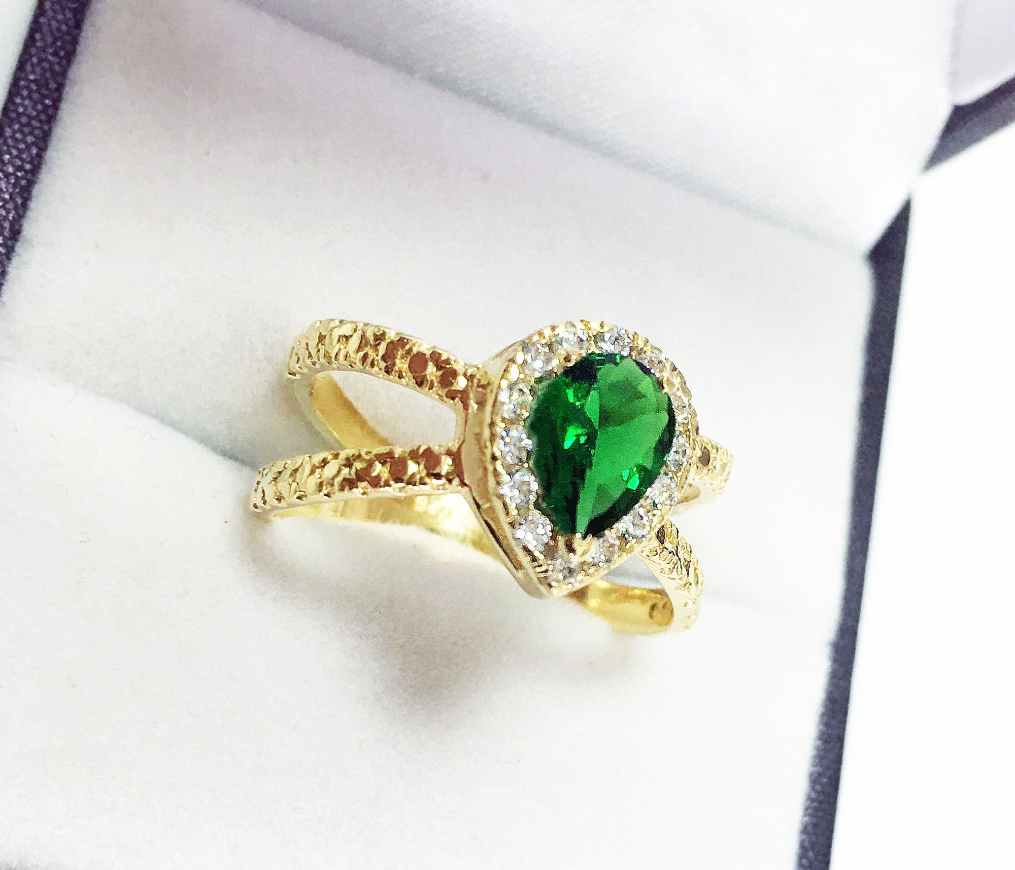 The spectacular design of this emerald ring is a contemporary take on a classic choice which will be much loved by anyone who loves bright and bold jewelry. The pear cut emerald is flanked on every side by high quality clear quartz gemstones.