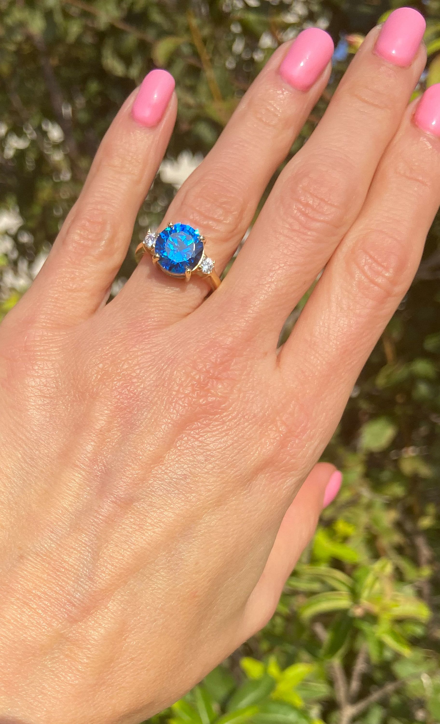 This gorgeous and elegant women&#39;s ring features a round-cut blue topaz gemstone with two round-cut dazzling clear quartz. This beautiful ring is enhanced with a high polish finish.