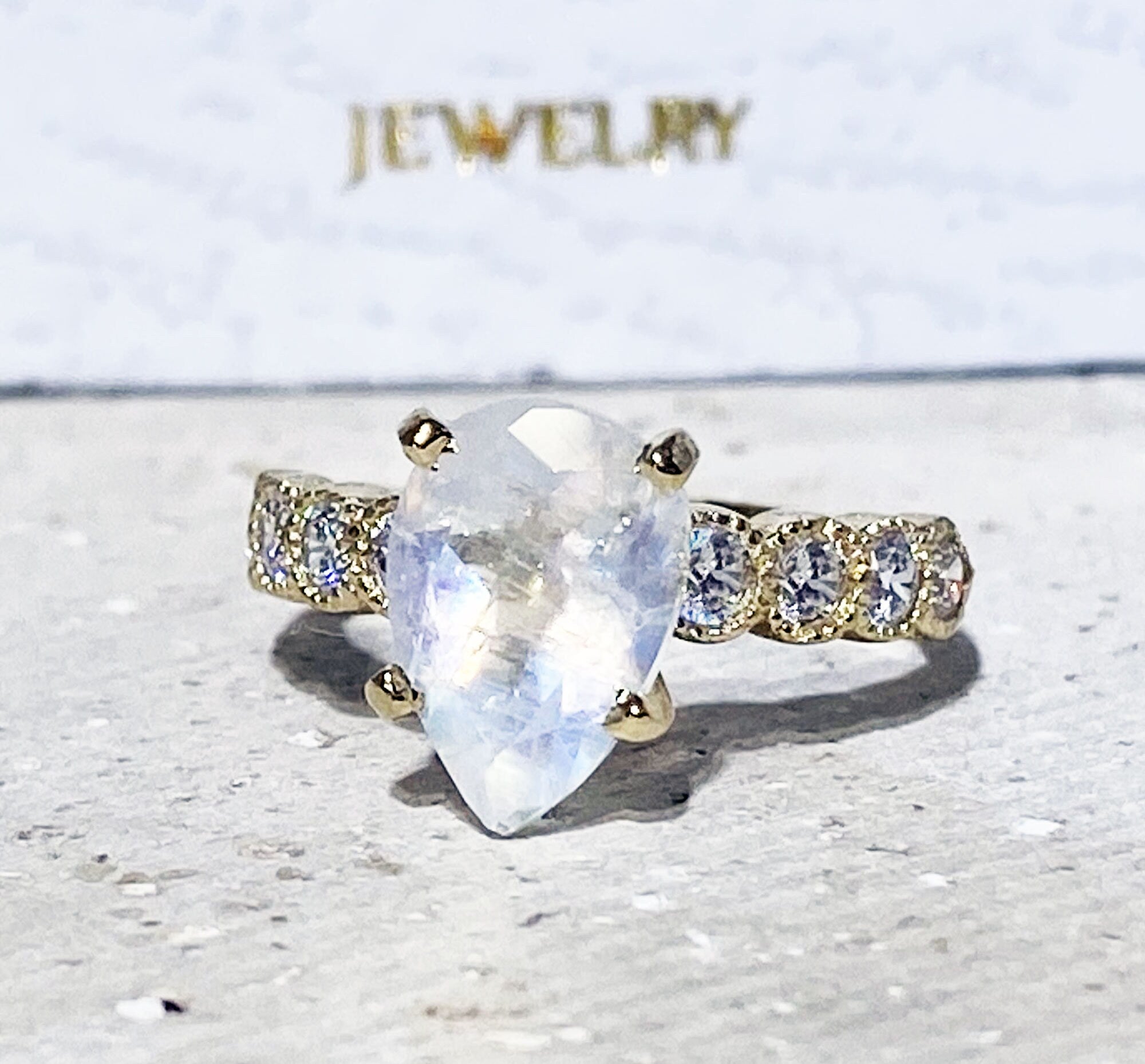 An absolute stunner, classic natural moonstone engagement ring with a pear cut gemstone of your choice as it’s centre stone and with round cut clear quartz on the band to further accentuate it.