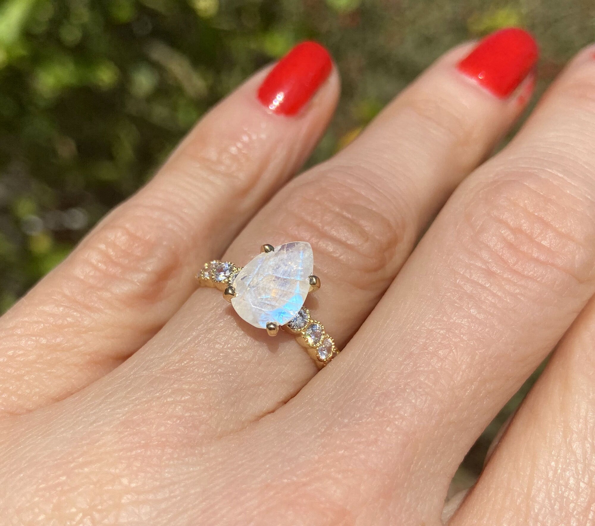 An absolute stunner, classic natural moonstone engagement ring with a pear cut gemstone of your choice as it’s centre stone and with round cut clear quartz on the band to further accentuate it.