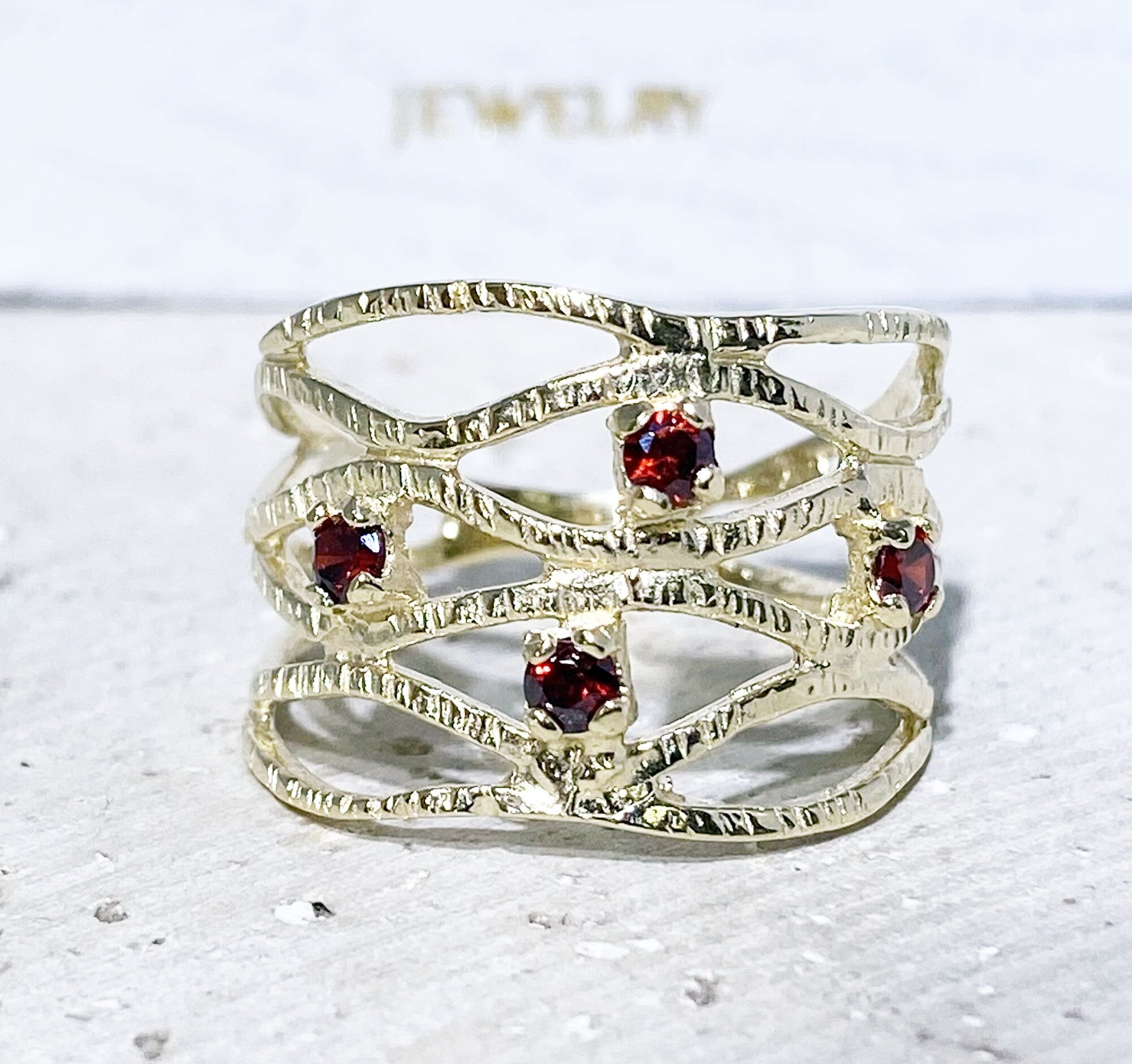 This gorgeous garnet ring displays simple elegance in its design. The ring features a round-cut natural red garnet gemstone and finished with a hammered band.