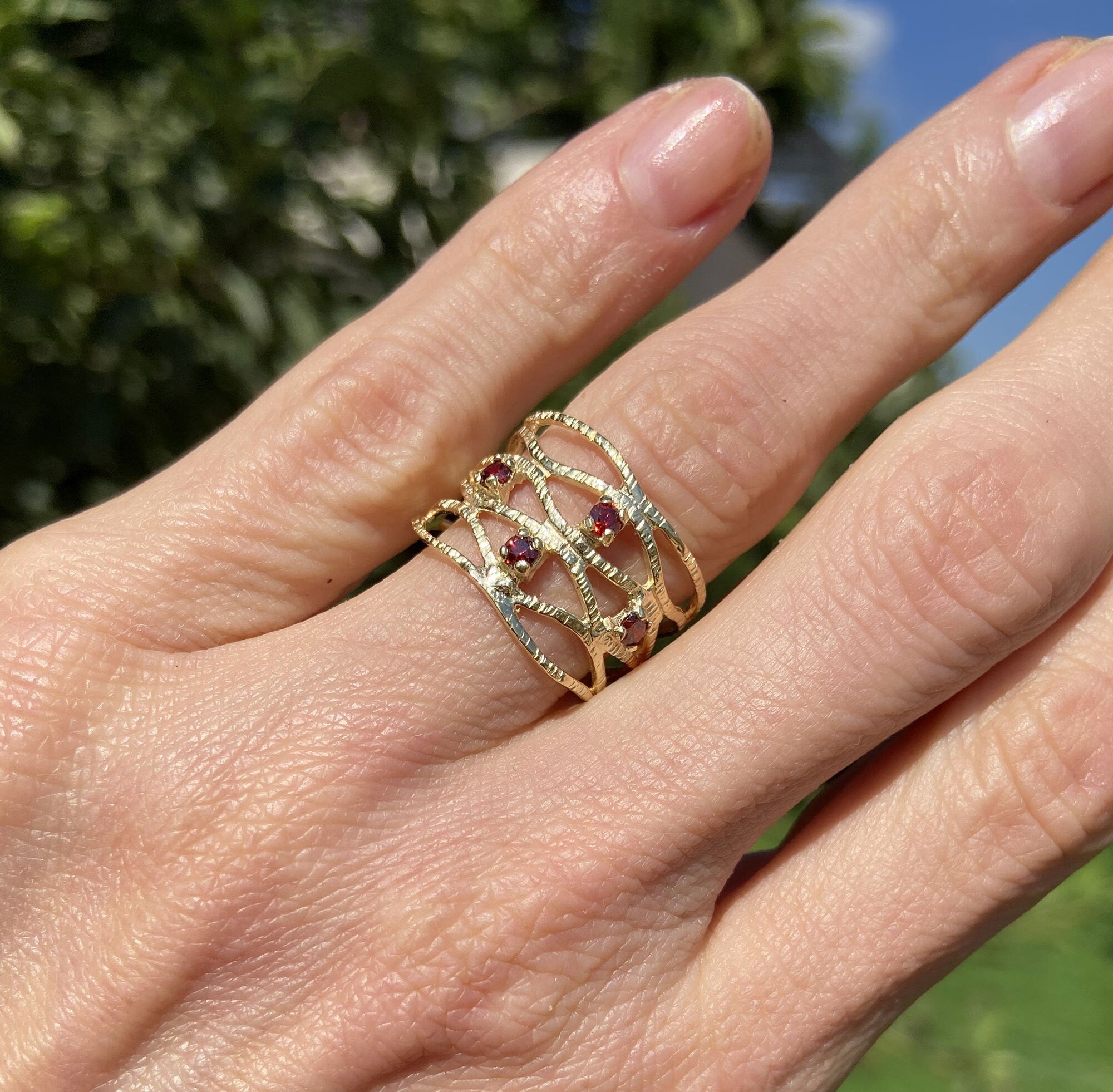 This gorgeous garnet ring displays simple elegance in its design. The ring features a round-cut natural red garnet gemstone and finished with a hammered band.