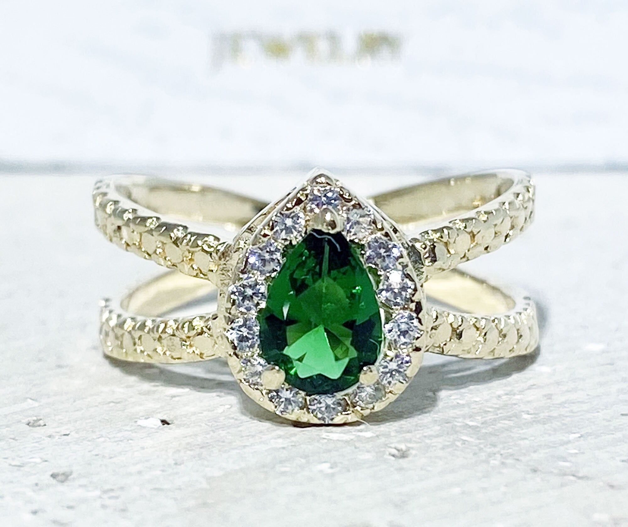 The spectacular design of this emerald ring is a contemporary take on a classic choice which will be much loved by anyone who loves bright and bold jewelry. The pear cut emerald is flanked on every side by high quality clear quartz gemstones.