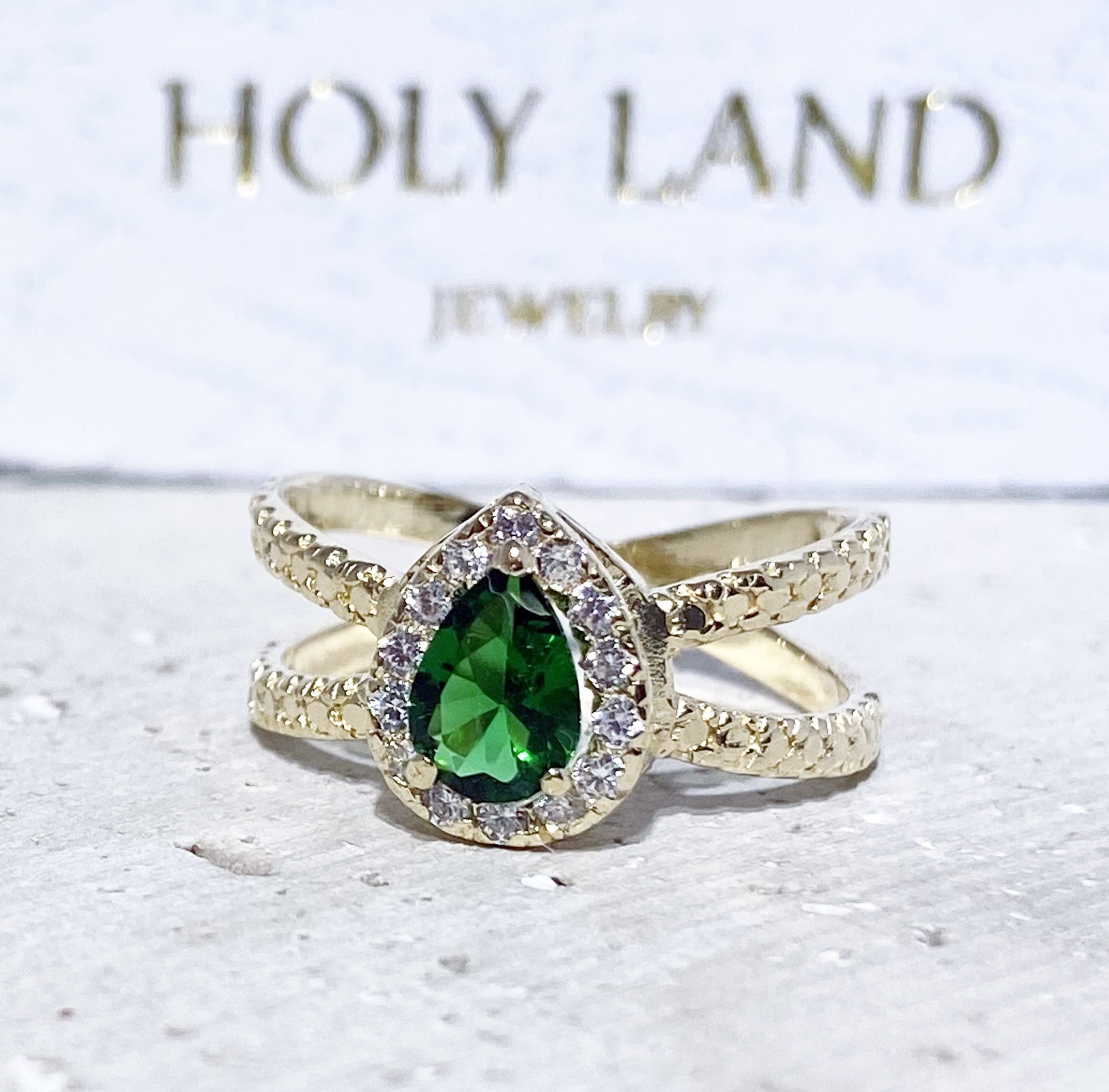 The spectacular design of this emerald ring is a contemporary take on a classic choice which will be much loved by anyone who loves bright and bold jewelry. The pear cut emerald is flanked on every side by high quality clear quartz gemstones.