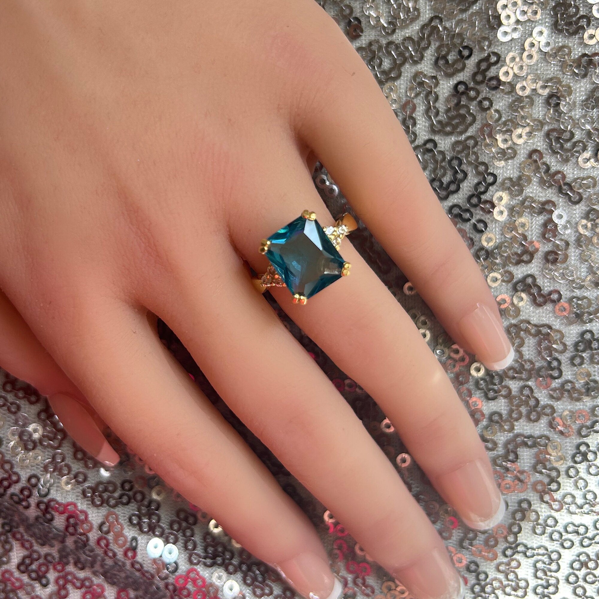 An absolute stunner, classic blue topaz engagement ring with an emerald cut gemstone of your choice as it’s centre stone and with round cut clear quartz on the band to further accentuate it.