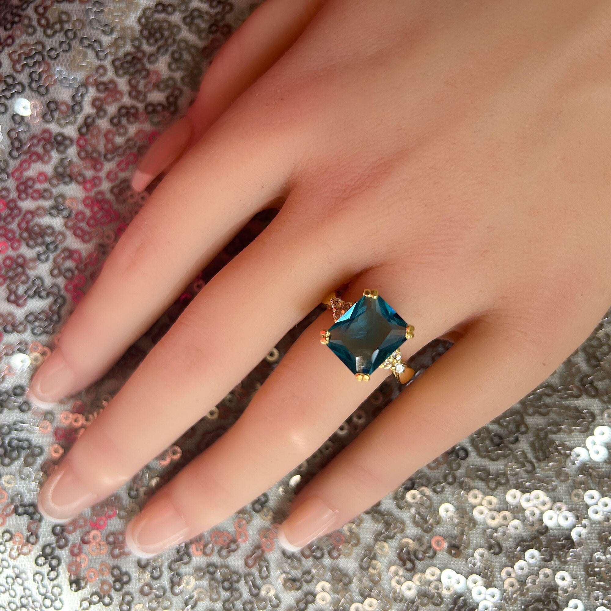 An absolute stunner, classic blue topaz engagement ring with an emerald cut gemstone of your choice as it’s centre stone and with round cut clear quartz on the band to further accentuate it.