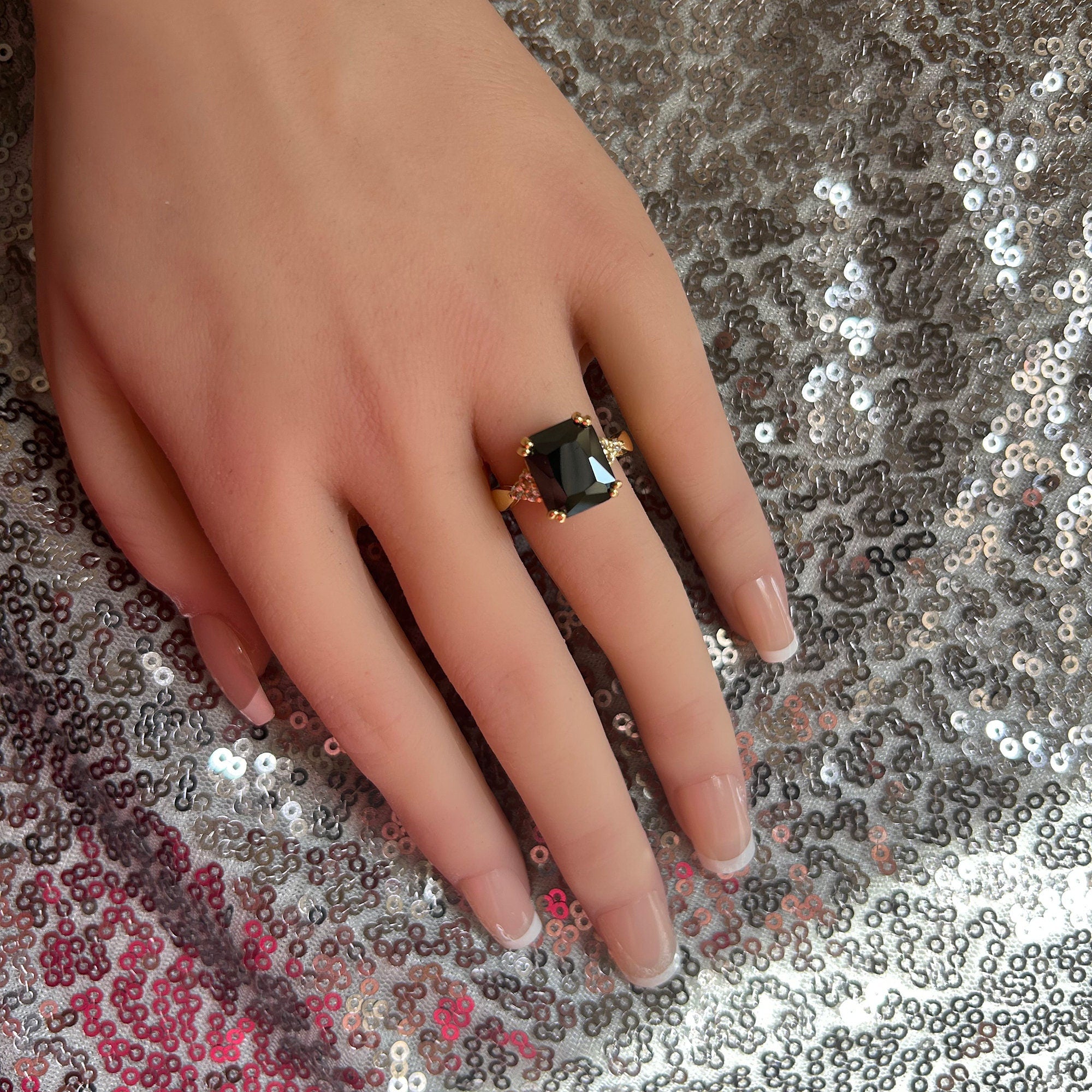 An absolute stunner, classic black onyx engagement ring with an emerald cut gemstone of your choice as it’s centre stone and with round cut clear quartz on the band to further accentuate it.