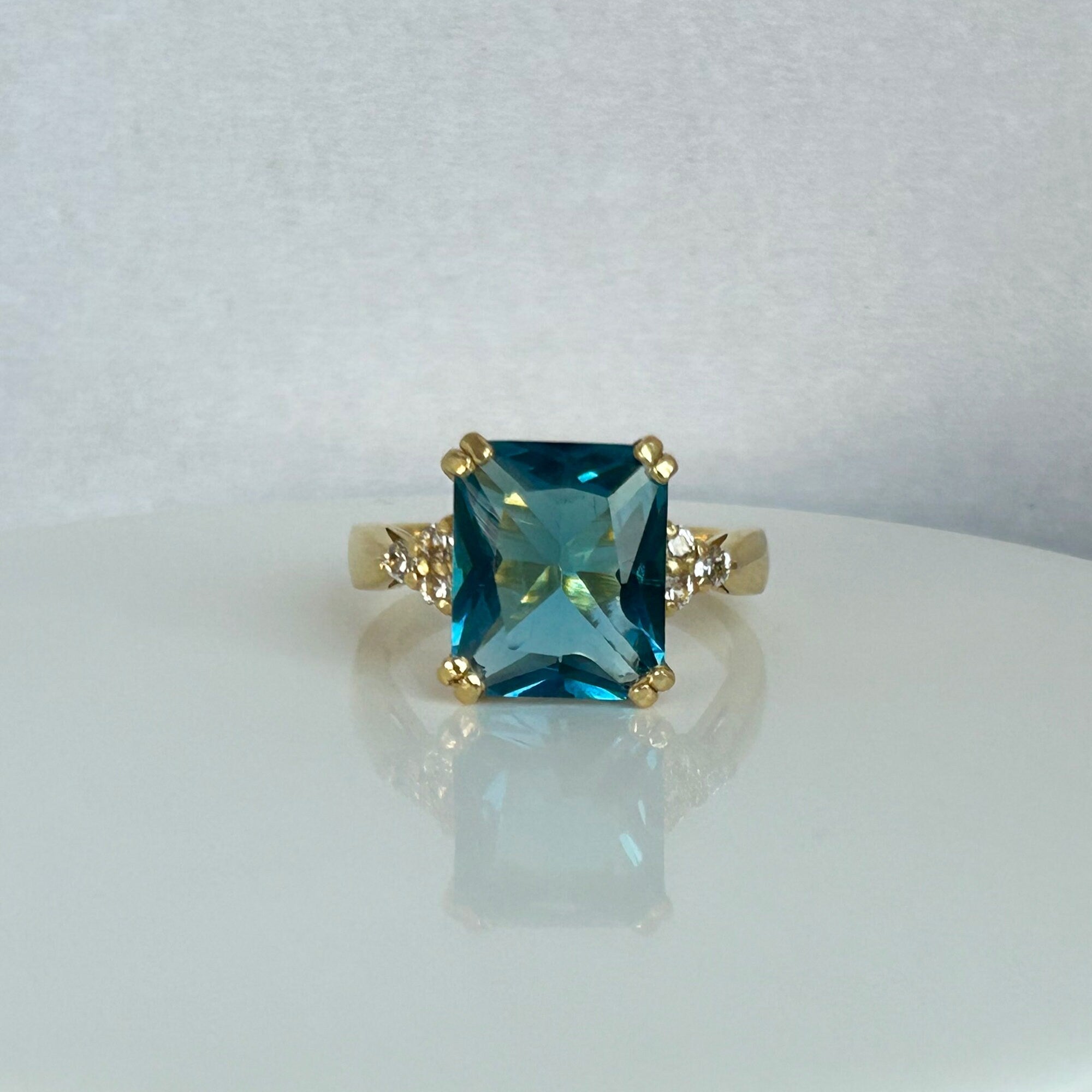 An absolute stunner, classic blue topaz engagement ring with an emerald cut gemstone of your choice as it’s centre stone and with round cut clear quartz on the band to further accentuate it.