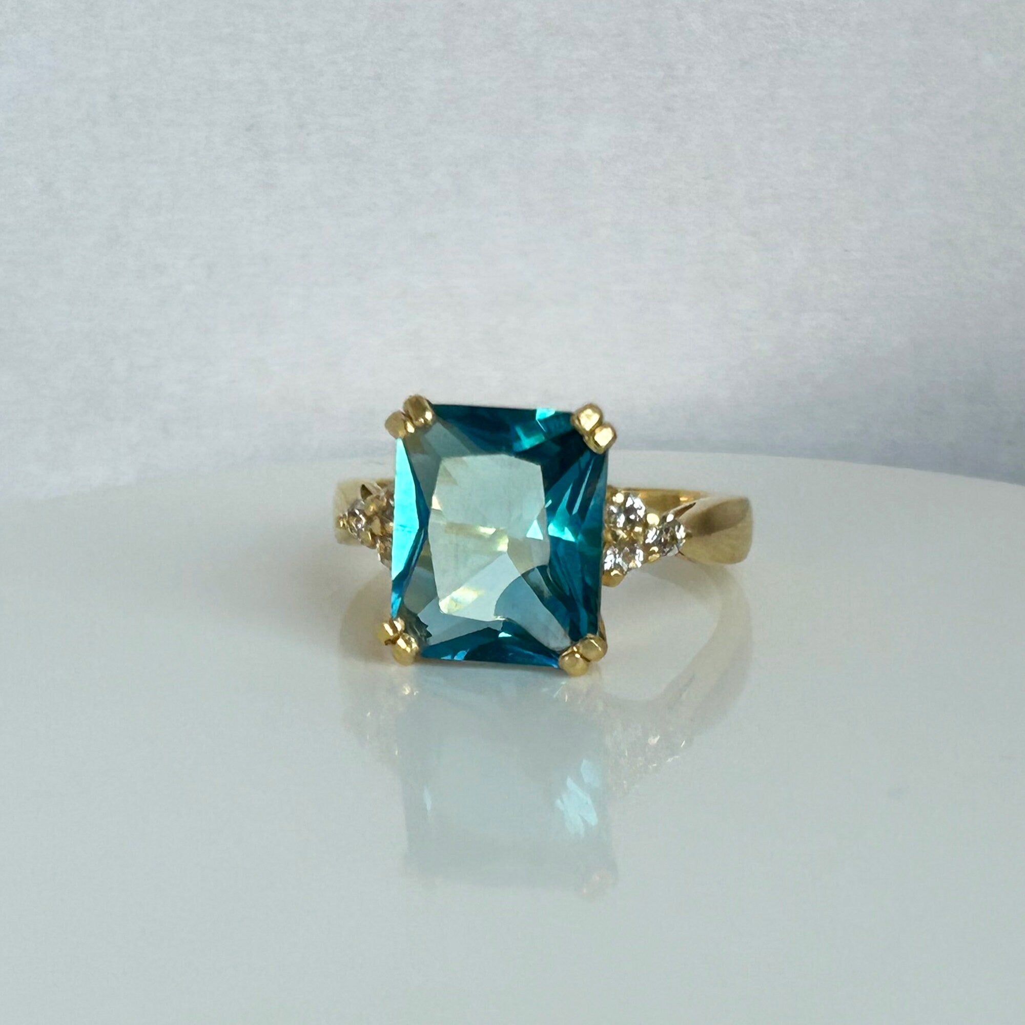 An absolute stunner, classic blue topaz engagement ring with an emerald cut gemstone of your choice as it’s centre stone and with round cut clear quartz on the band to further accentuate it.