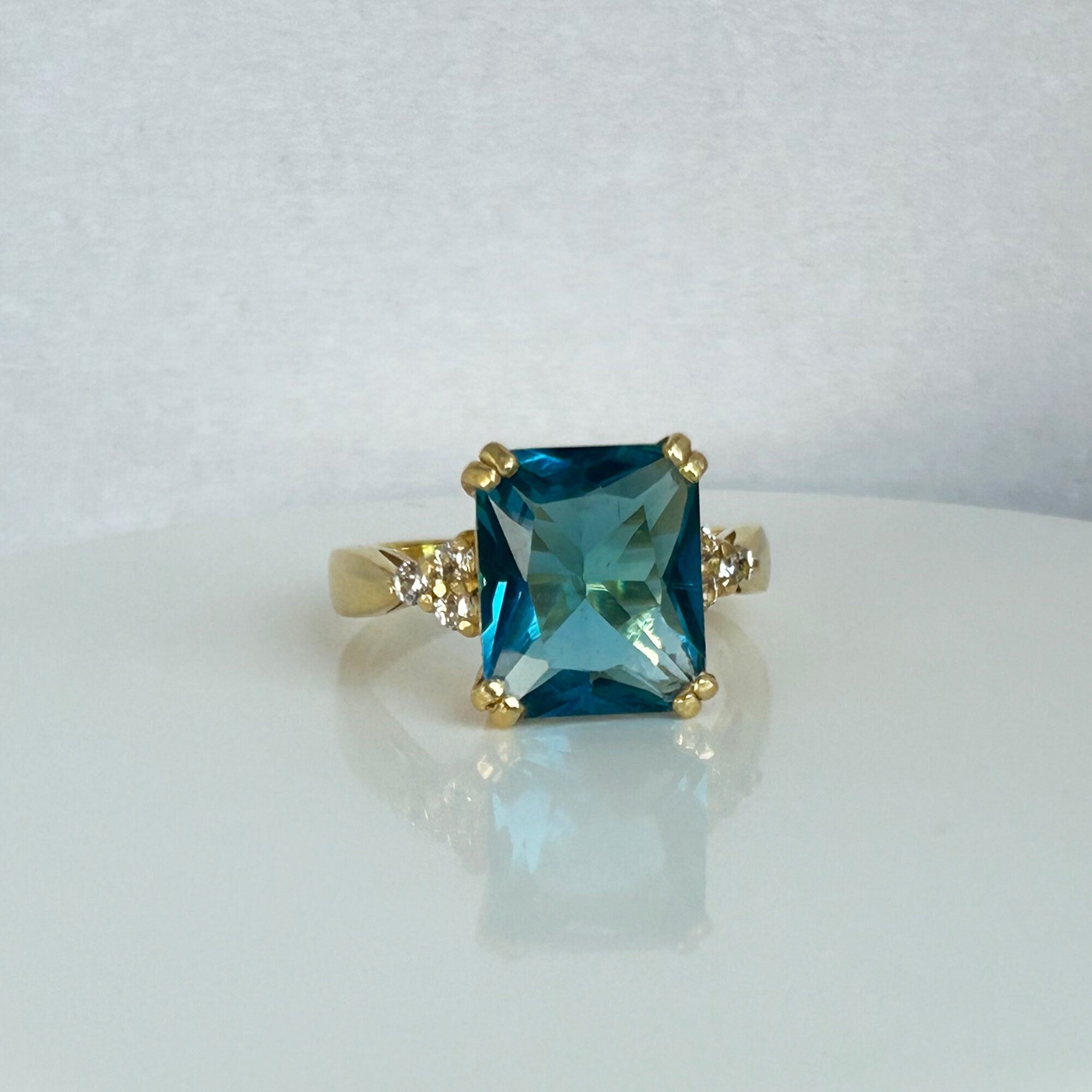 An absolute stunner, classic blue topaz engagement ring with an emerald cut gemstone of your choice as it’s centre stone and with round cut clear quartz on the band to further accentuate it.