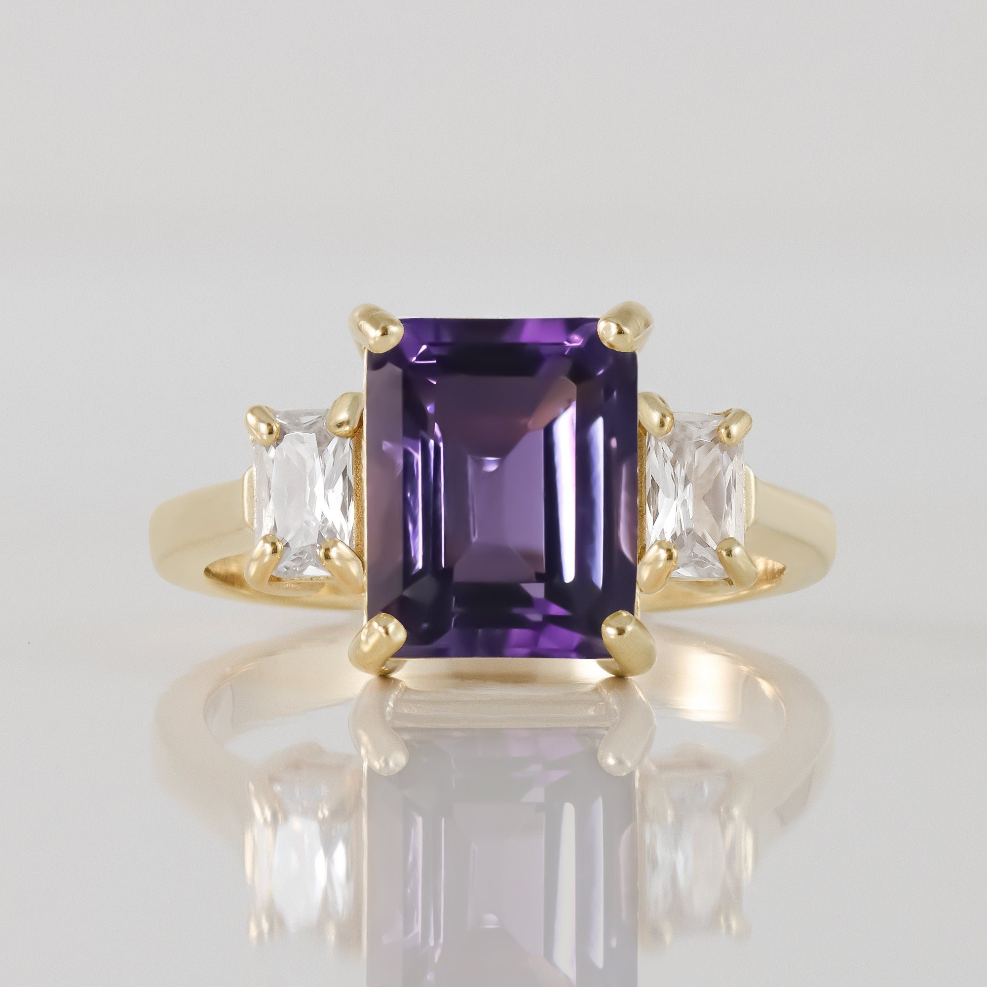 An absolute stunner, classic natural purple amethyst engagement ring with an emerald cut gemstone of your choice as it’s centre stone and with clear quartz on the band to further accentuate it.