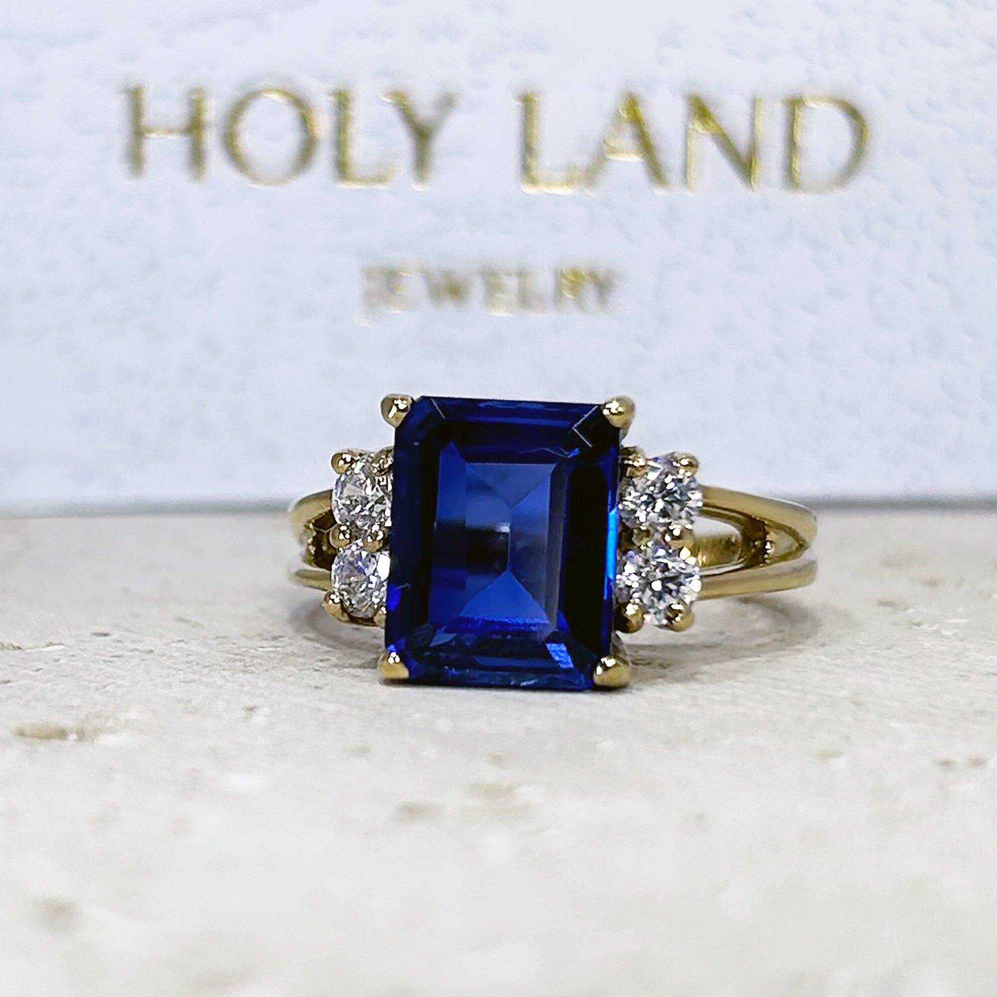 An absolute stunner, classic blue sapphire engagement ring with an emerald cut gemstone of your choice as it’s centre stone and with round cut clear quartz on the band to further accentuate it.