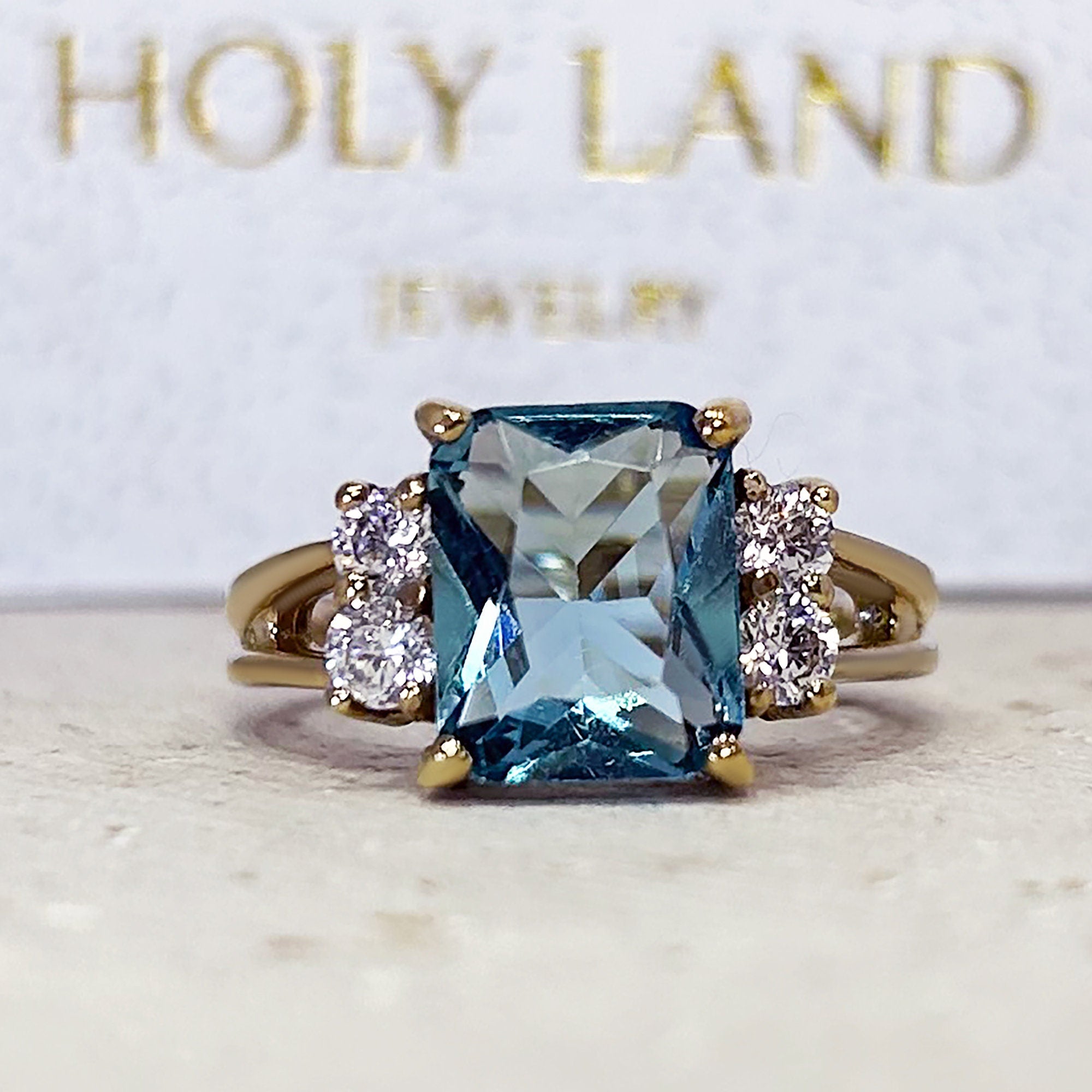 An absolute stunner, classic blue topaz engagement ring with an emerald cut gemstone of your choice as it’s centre stone and with round cut clear quartz on the band to further accentuate it.