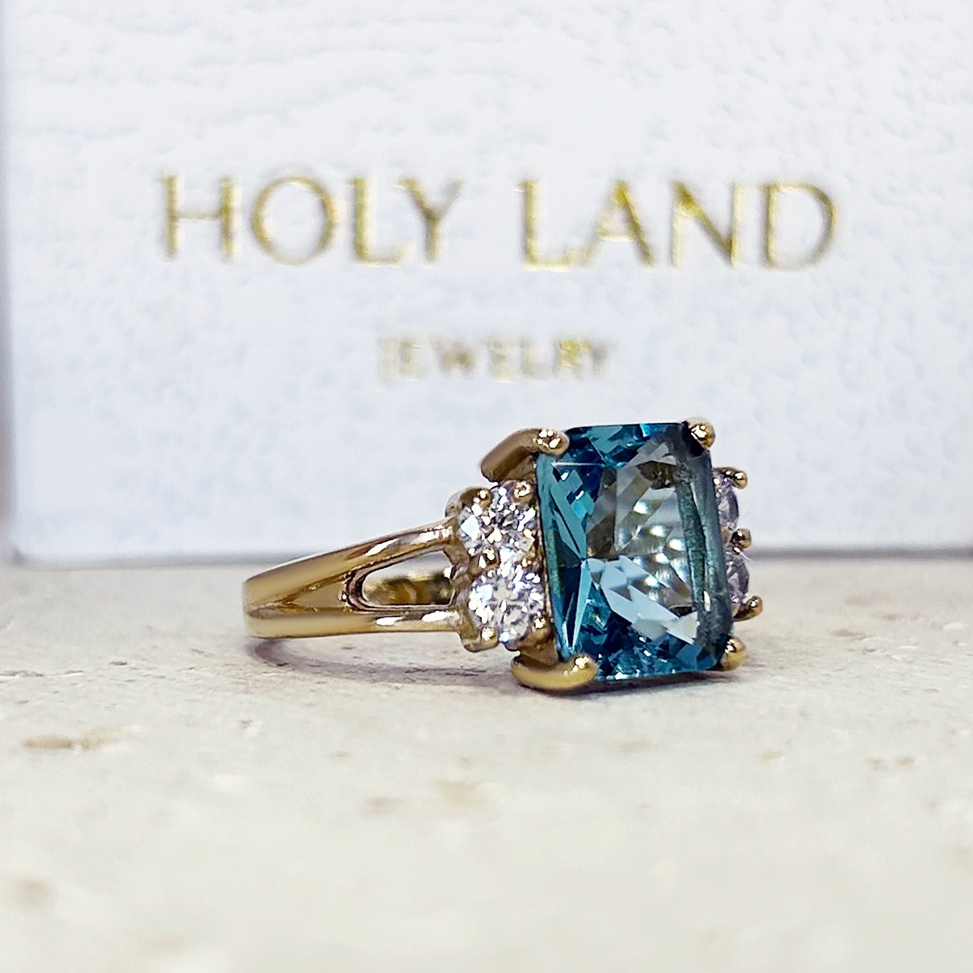 An absolute stunner, classic blue topaz engagement ring with an emerald cut gemstone of your choice as it’s centre stone and with round cut clear quartz on the band to further accentuate it.